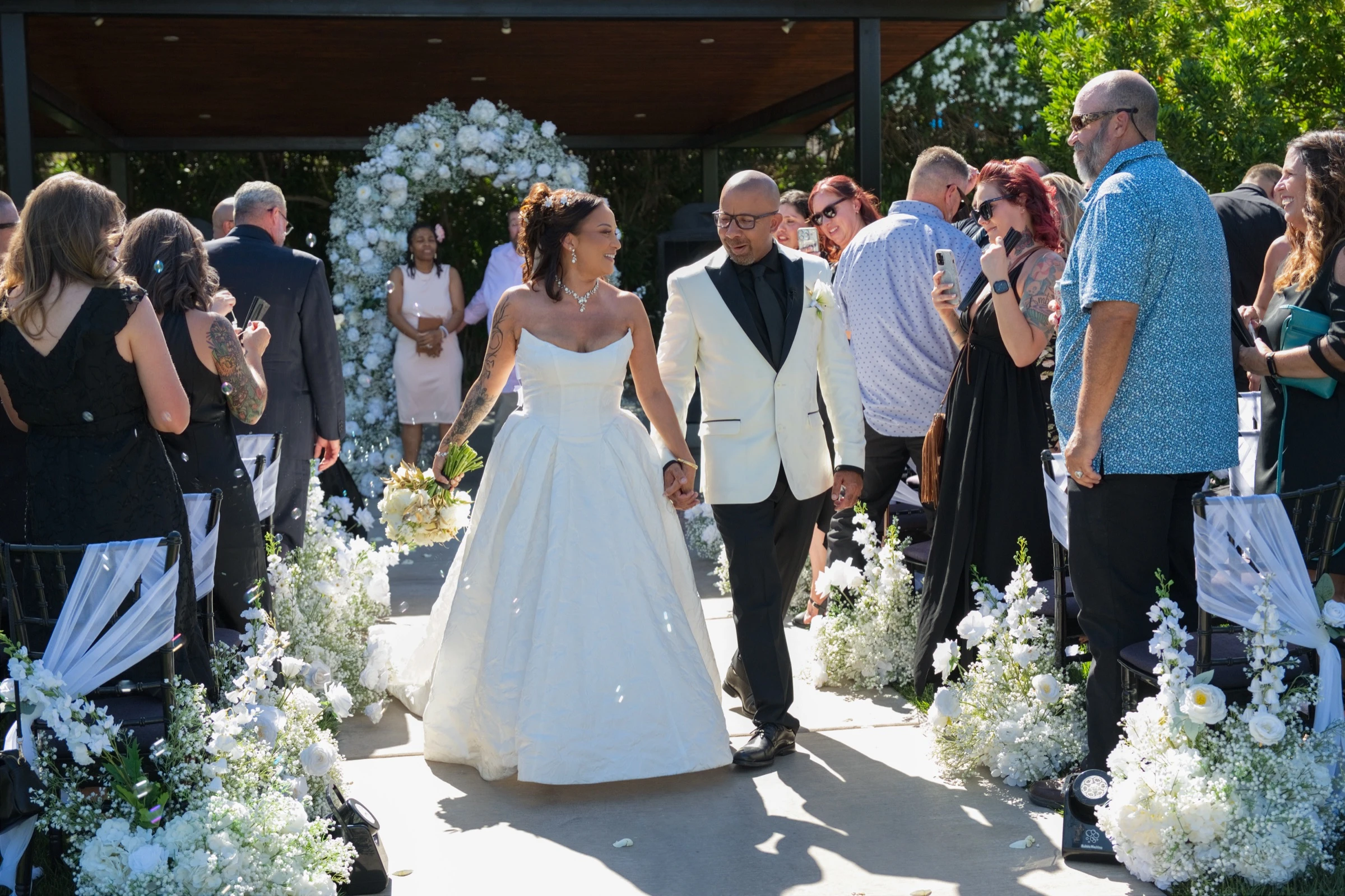 Newlyweds walking hand in hand through their guests after an outdoor ceremony