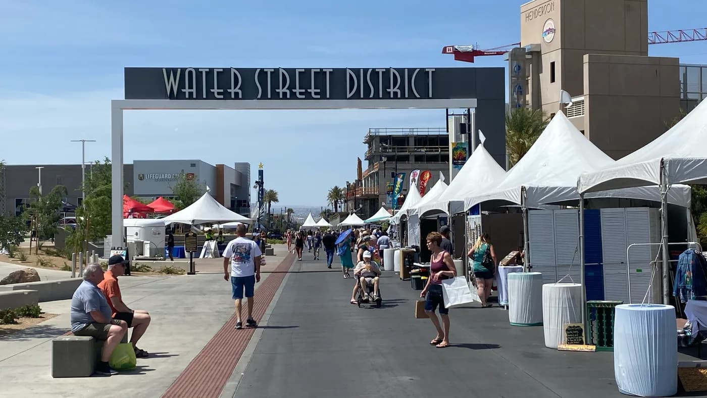 Visitors and market tents beneath the Water Street District sign in Henderson